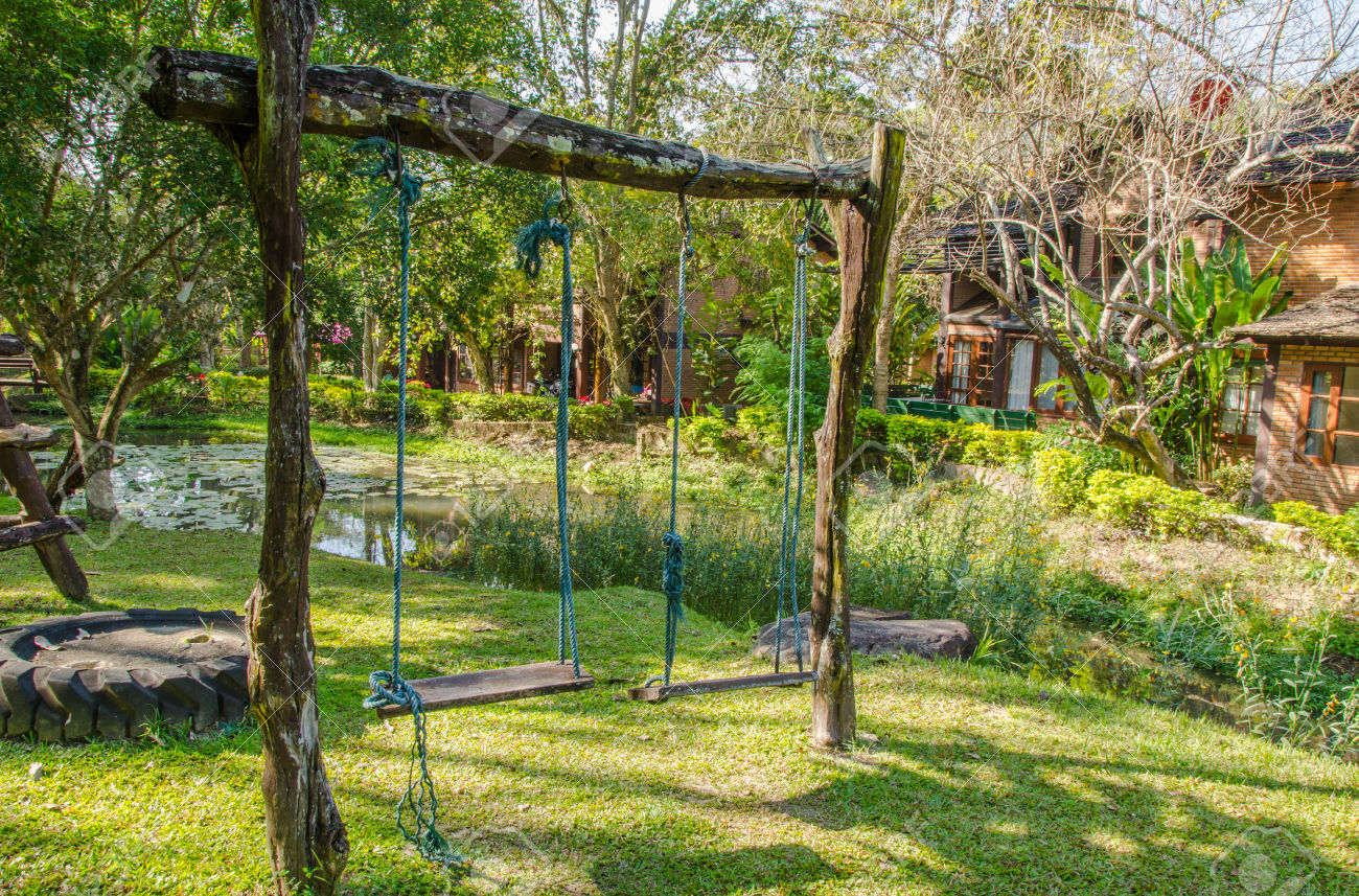 wood playground swing hanging in green grass field